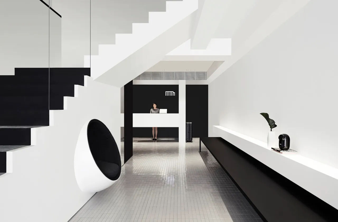 A modern, minimalist reception area with a metal staircase and desk.