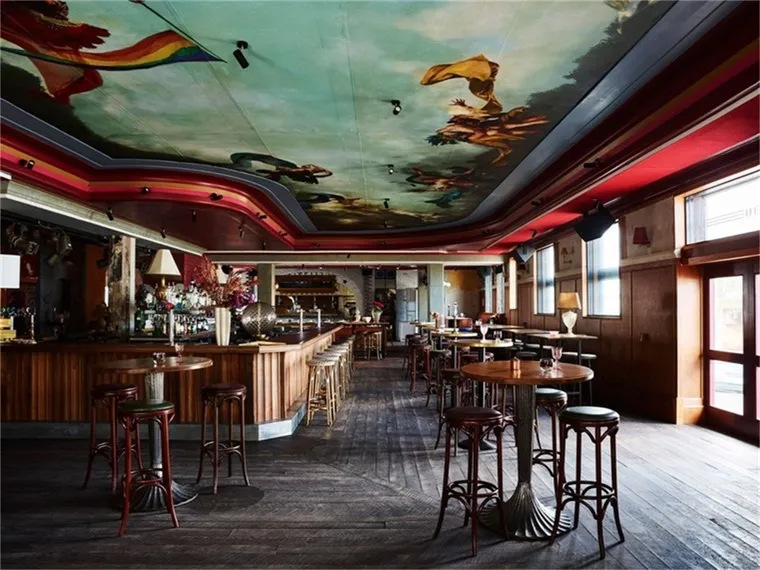 An empty restaurant interior with wooden ceiling and metal stools