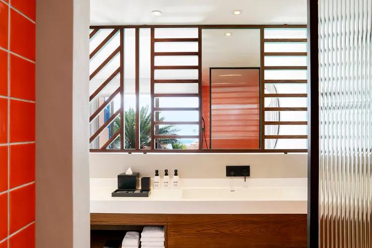Modern minimalist bathroom featuring glass tiles and wood elements.