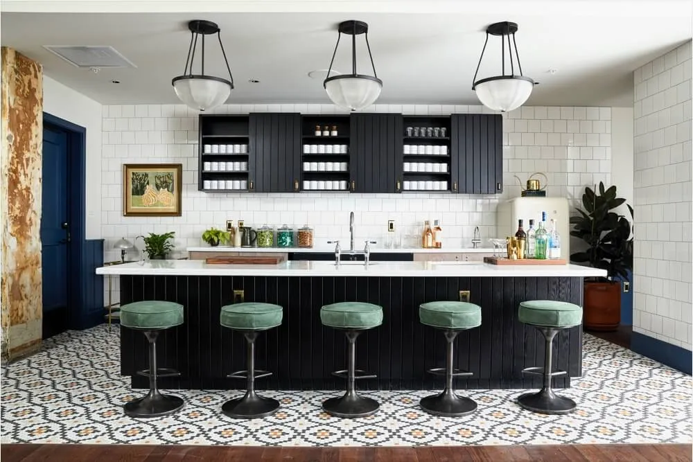 Modern kitchen with black cabinets, patterned tile flooring, and bar stools