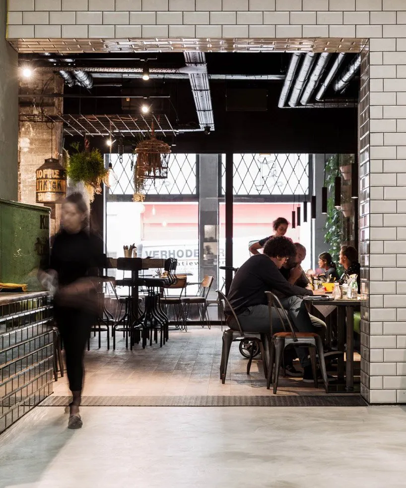Interior of a modern cafe with metal chairs, glass tabletops, and industrial decor