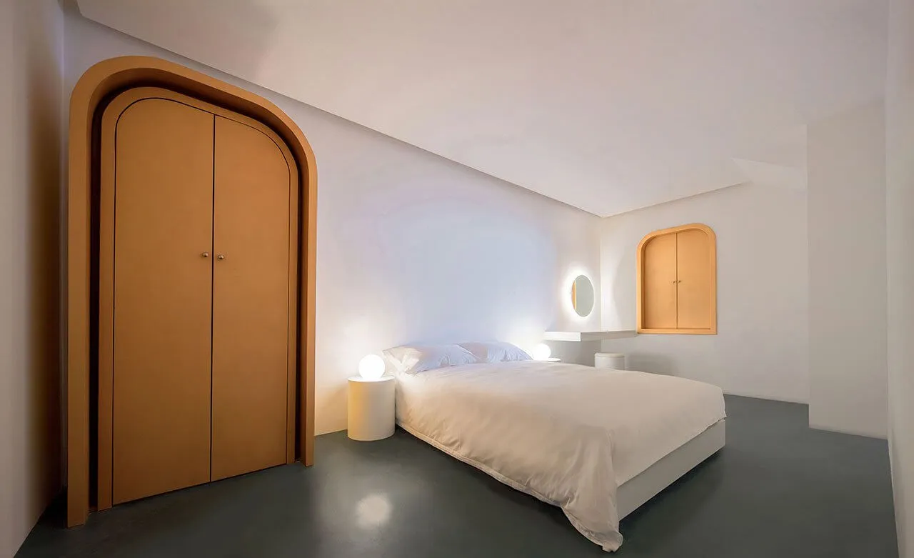 A modern minimalist bedroom with white furniture, a bed, and orange arched doors.