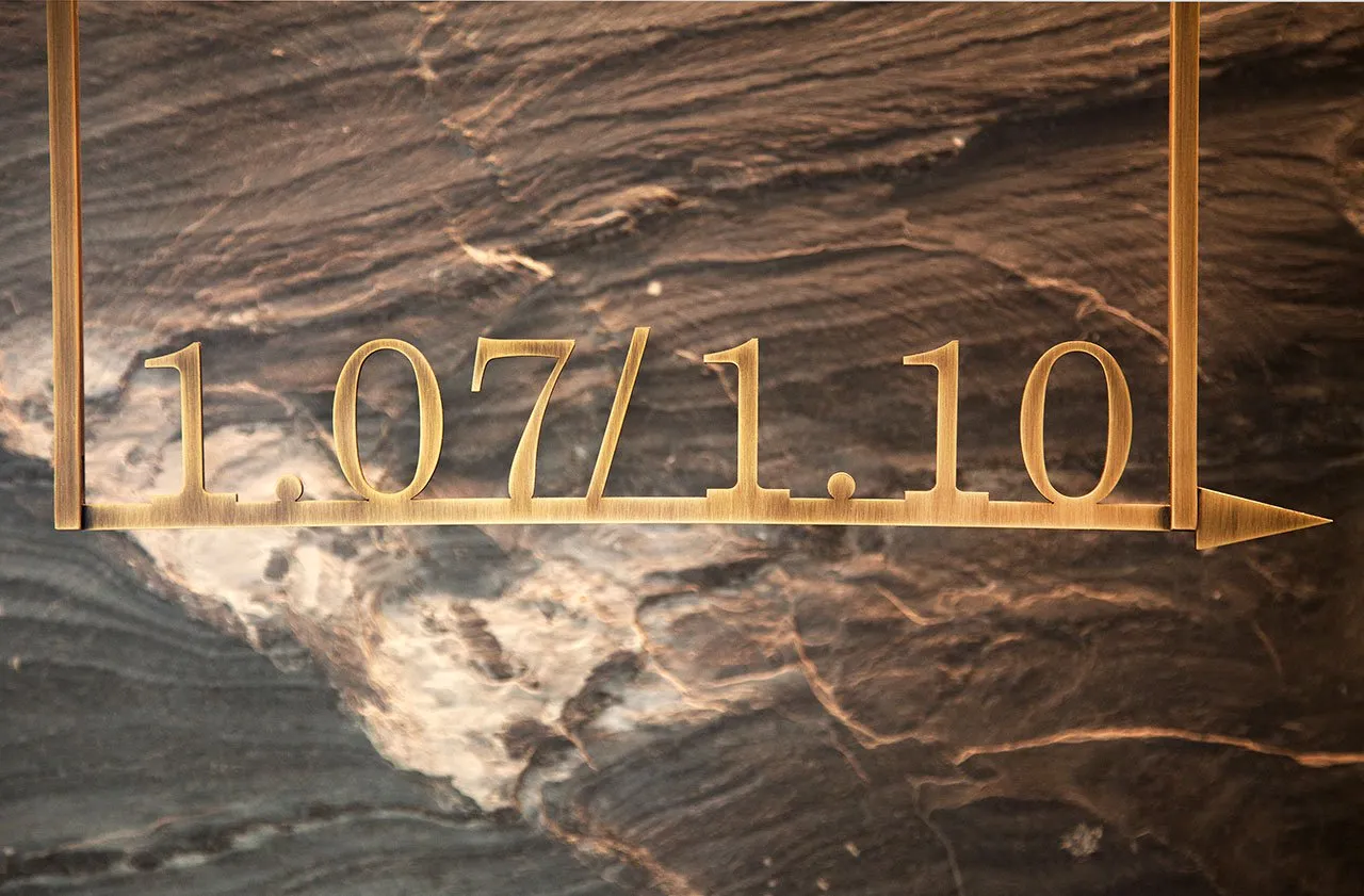 Gold-colored metal sign with date and arrow on marble background
