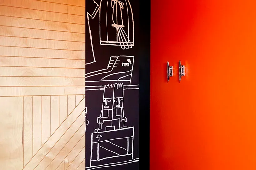 A close-up image of a door with a red wall, showcasing the texture and design of the wooden door and the vibrant orange wall.