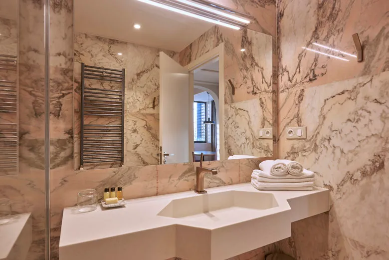 Modern bathroom with marble walls, a sink, and towels.