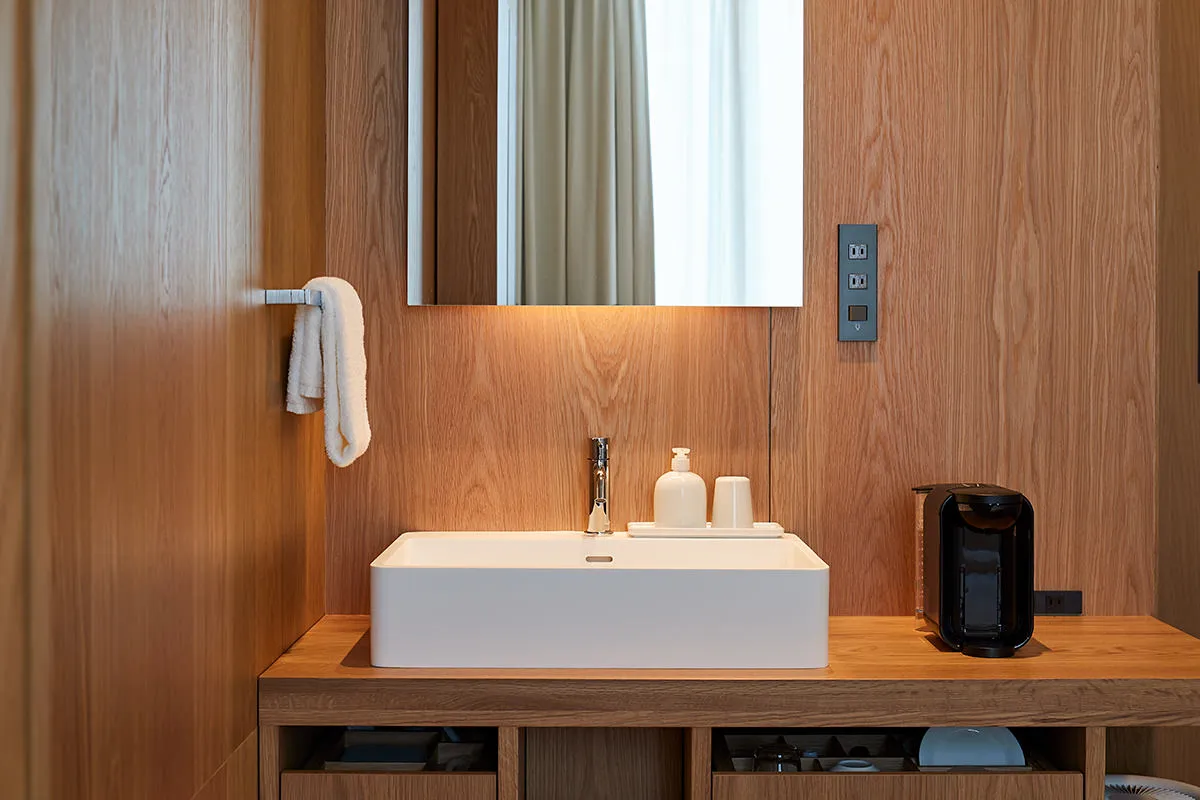 Modern bathroom with wooden walls, white countertop, and white sink.
