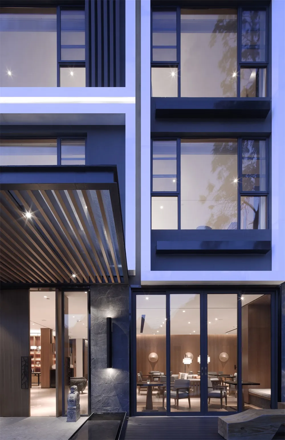 Modern building exterior with large glass windows, illuminated by interior lighting.