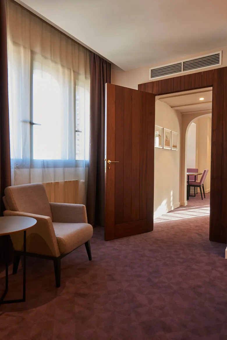 A modern hotel suite featuring wooden furnishings and a large window.