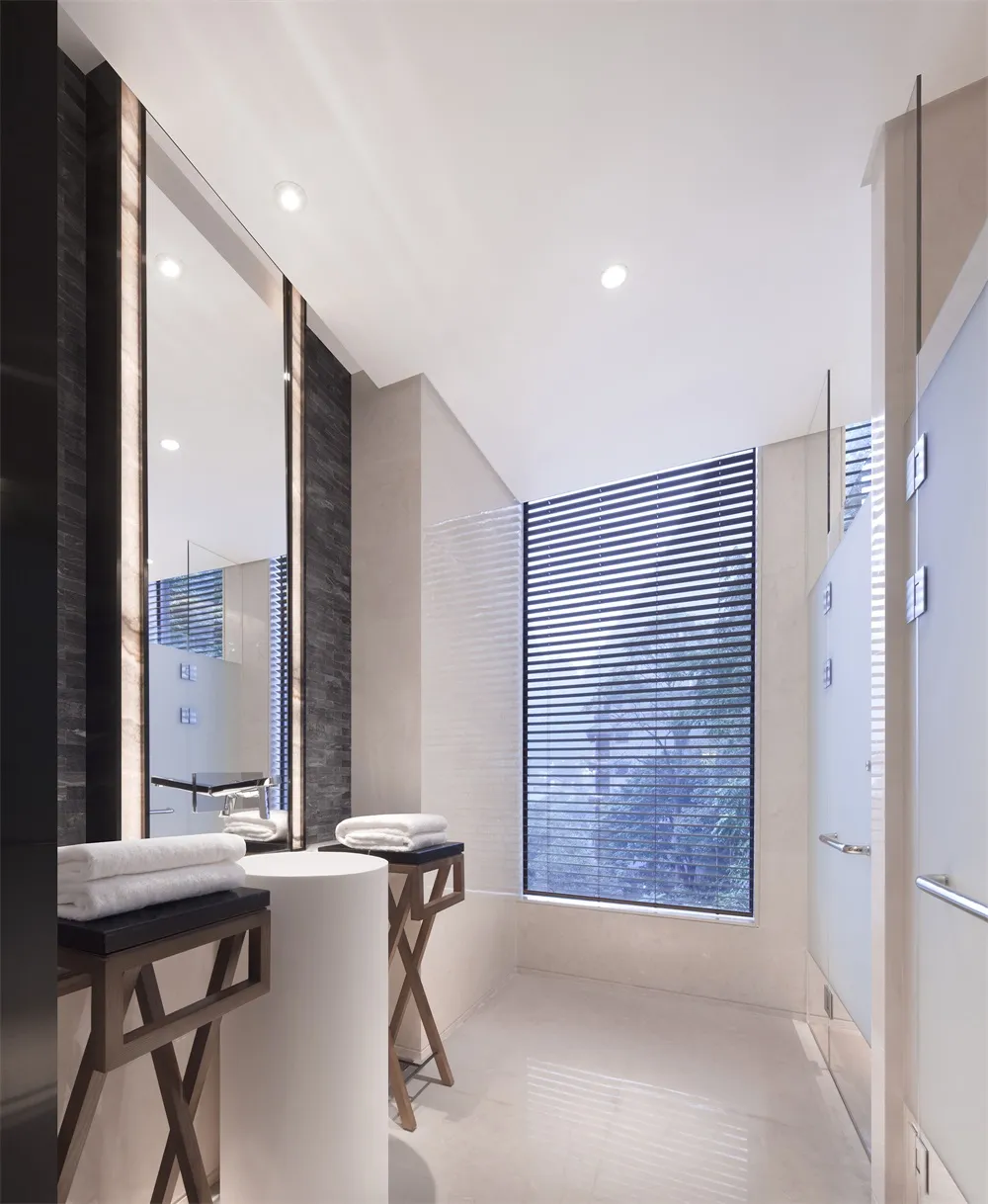 A modern bathroom featuring marble tiles and a large window with blinds.