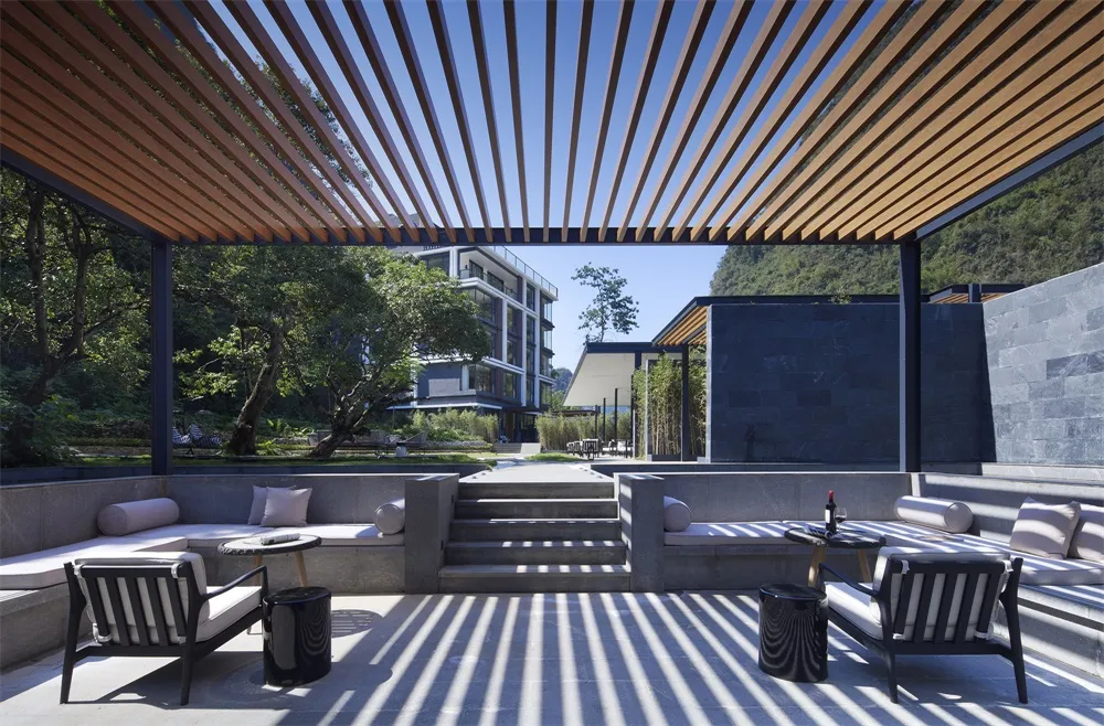A modern patio featuring furniture made of wood, concrete, and glass.