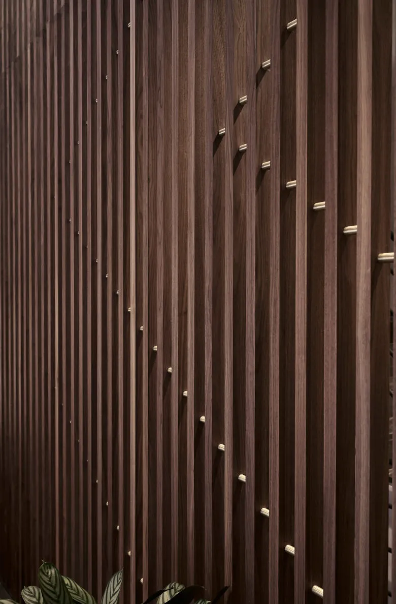 A close-up view of a wood-paneled wall with vertical slats and metallic accents.