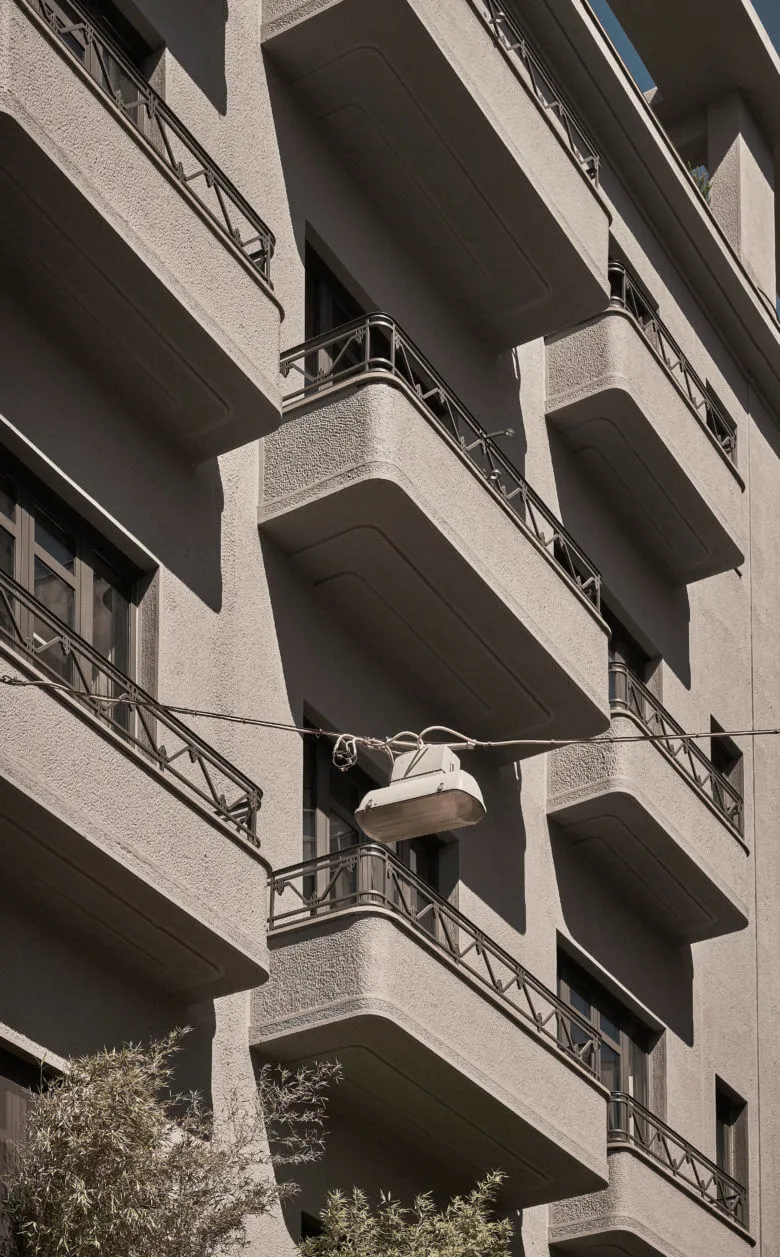 Concrete building with balconies and streetlight hanging from wire