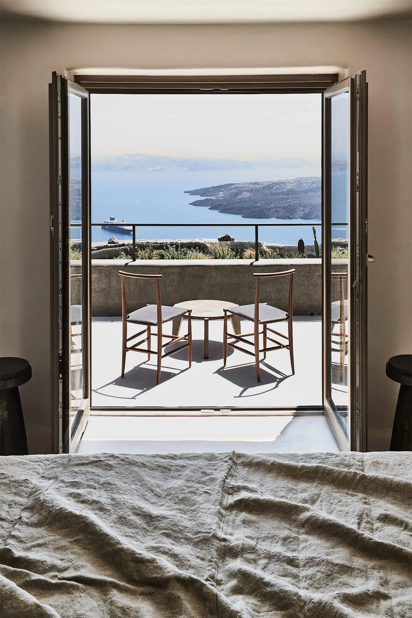A minimalist bedroom featuring wooden furniture and a view of the sea.