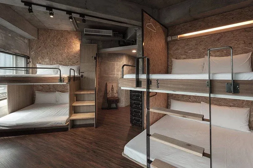 A modern minimalist bedroom with wooden bunk beds, white bedding, and a rustic ladder.