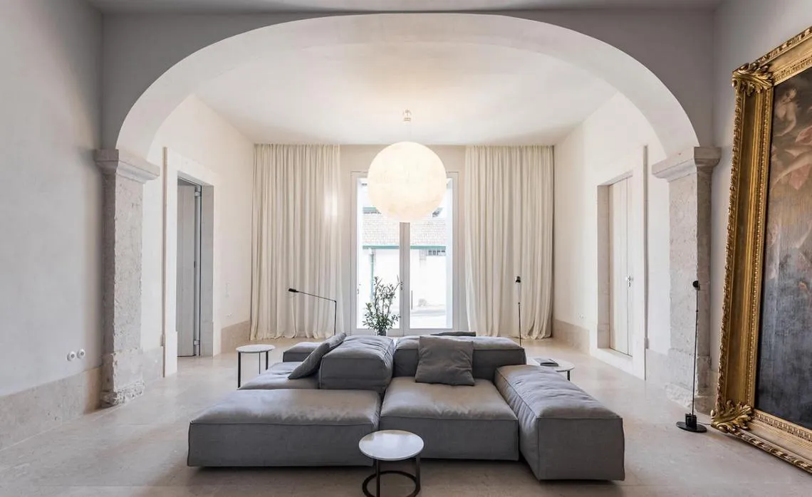 Modern, minimalist living room featuring a comfortable, sectional sofa with plush cushions and soft textiles, natural light f