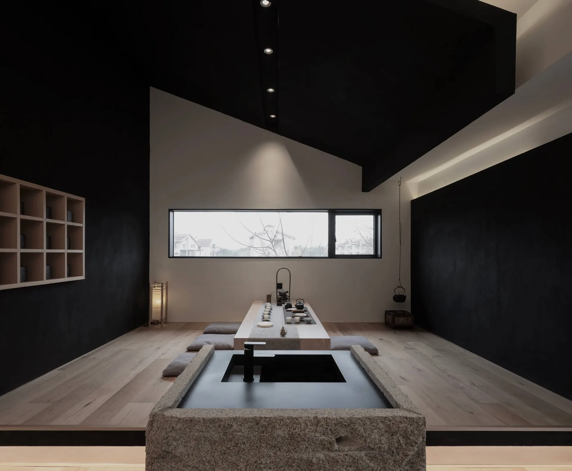 A minimalist tea room featuring teak furniture and a stone water basin.