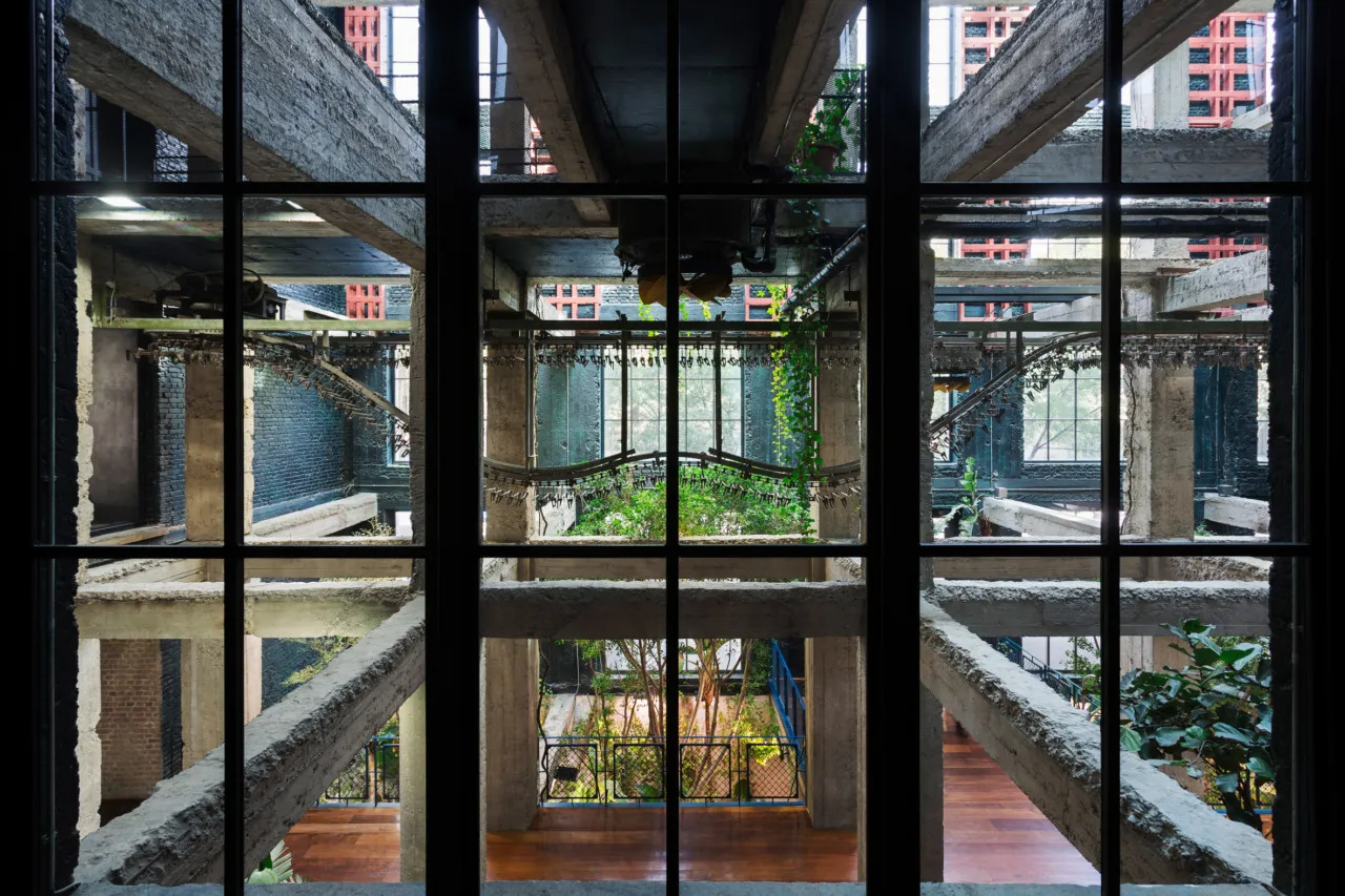 An industrial-style interior space with concrete architecture and greenery.