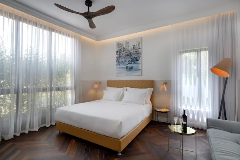 Modern bedroom featuring a wooden floor, fabric bed, and minimalist decor.