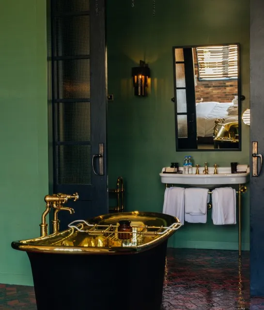 A modern bathroom with a black and gold bathtub, a golden faucet, and a white towel rack.