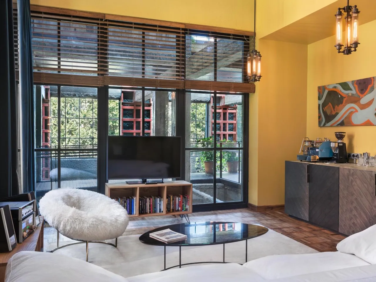 A modern living room with a glass coffee table, white couch, and wooden paneling on the walls and ceiling.