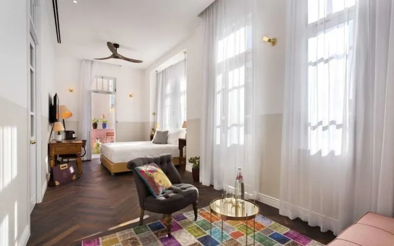 A modern residential interior design featuring a bedroom with wood furniture, cotton textiles, and a colorful rug.