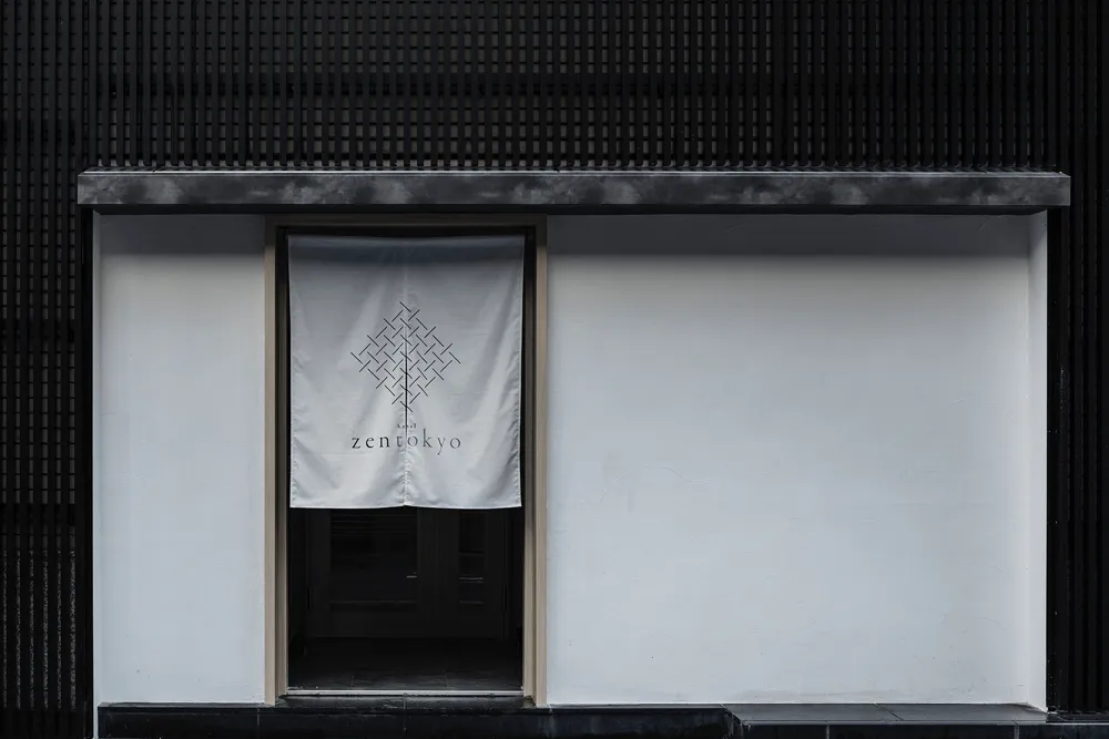 店面設有白色橫幅，上面有幾何圖案與「Zen Tokyo」文字。店面前方為白色牆面與