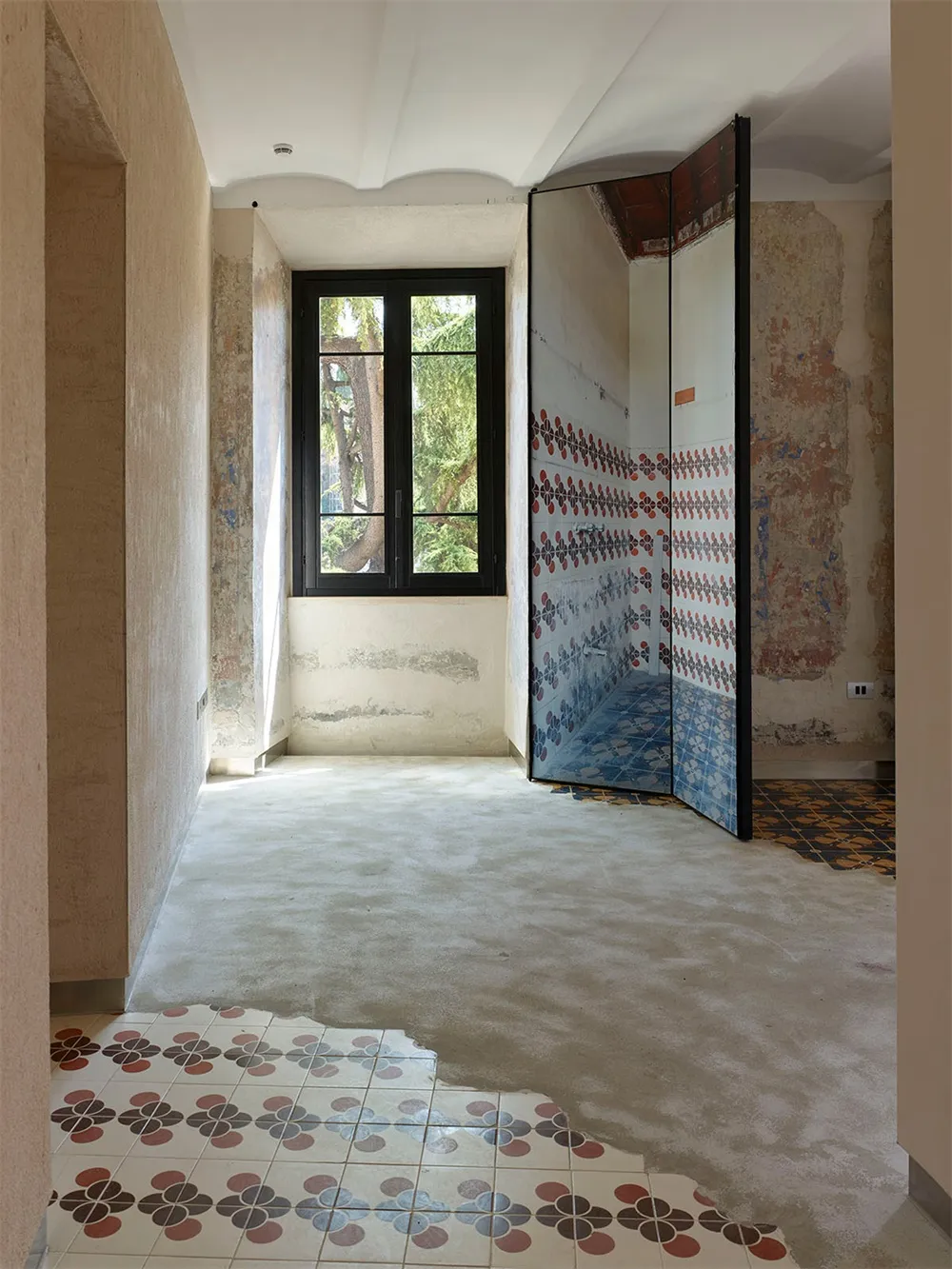 Concrete bathroom renovation with patterned tile floor and mosaic tile wall, featuring a modern shower enclosure.