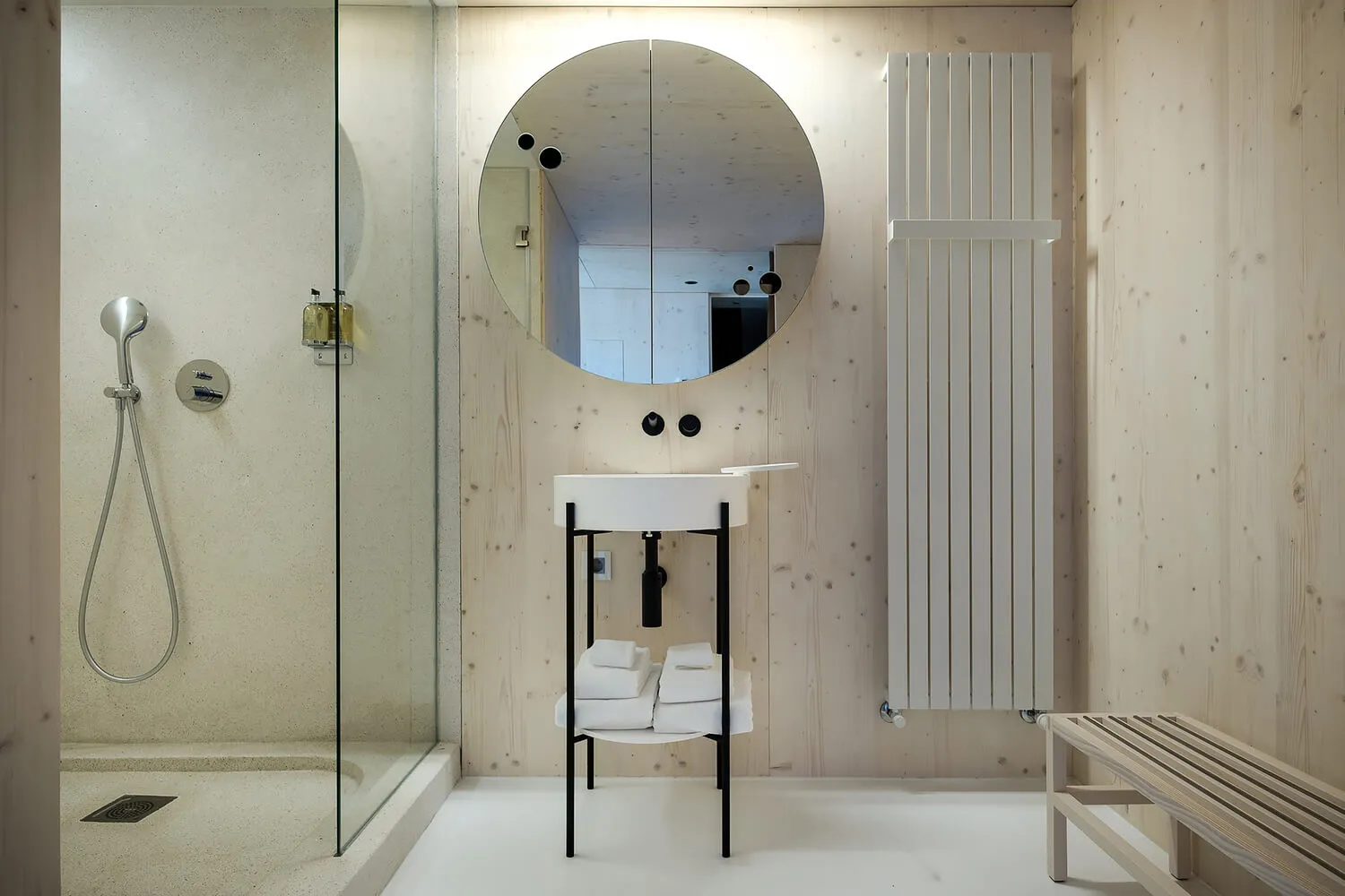 A minimalist bathroom with wooden walls, a white sink, and a glass shower enclosure.