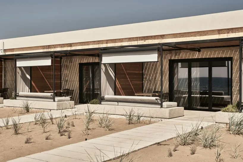 Modern, minimalist beachfront architecture featuring concrete materials and a spacious outdoor patio with comfortable seating