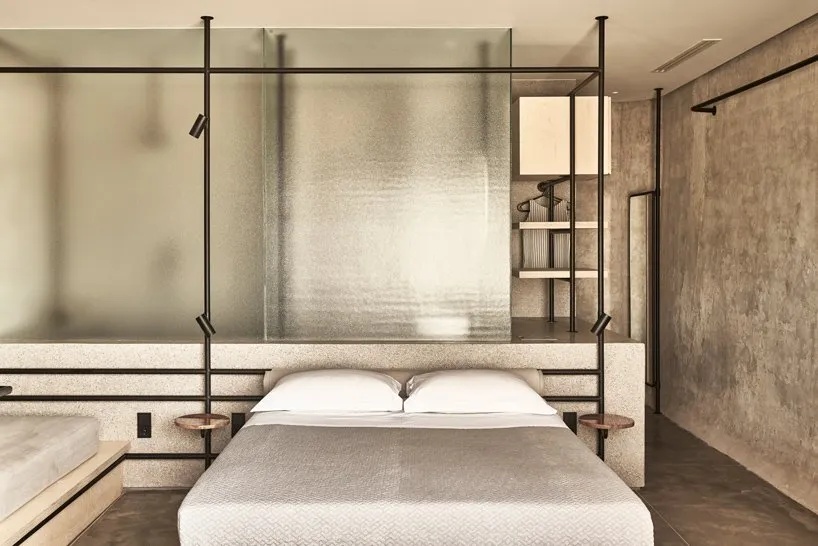 A modern minimalist bedroom with a concrete and metal headboard.