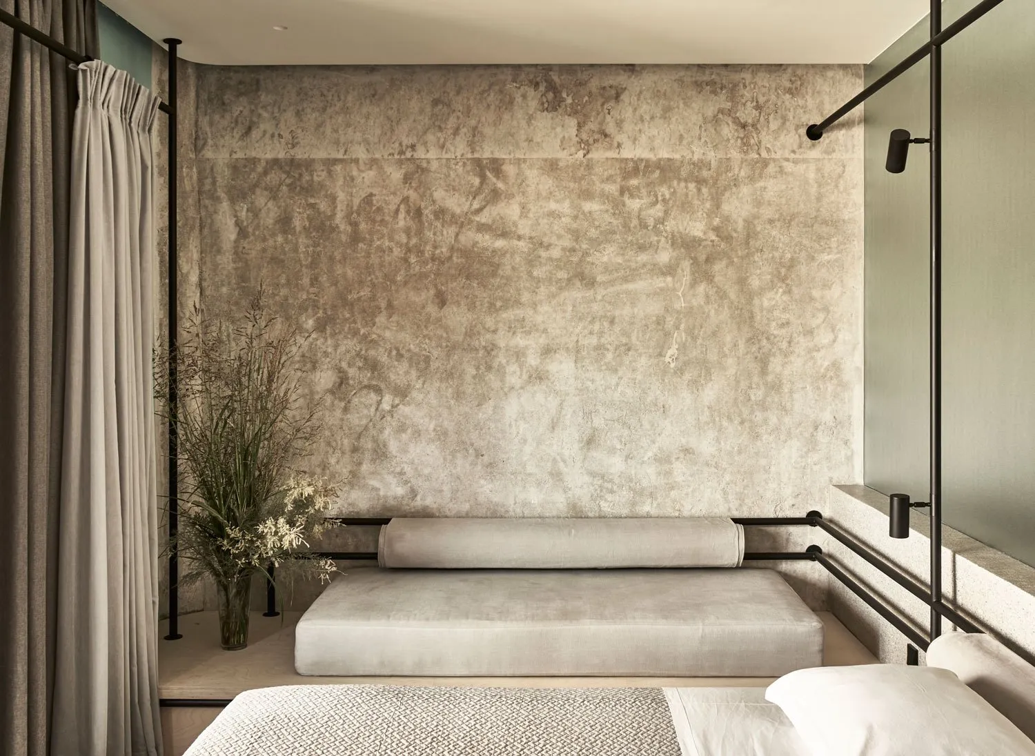 Modern minimalist bedroom with concrete and wood elements, featuring a bed with a concrete headboard and wooden headboard.