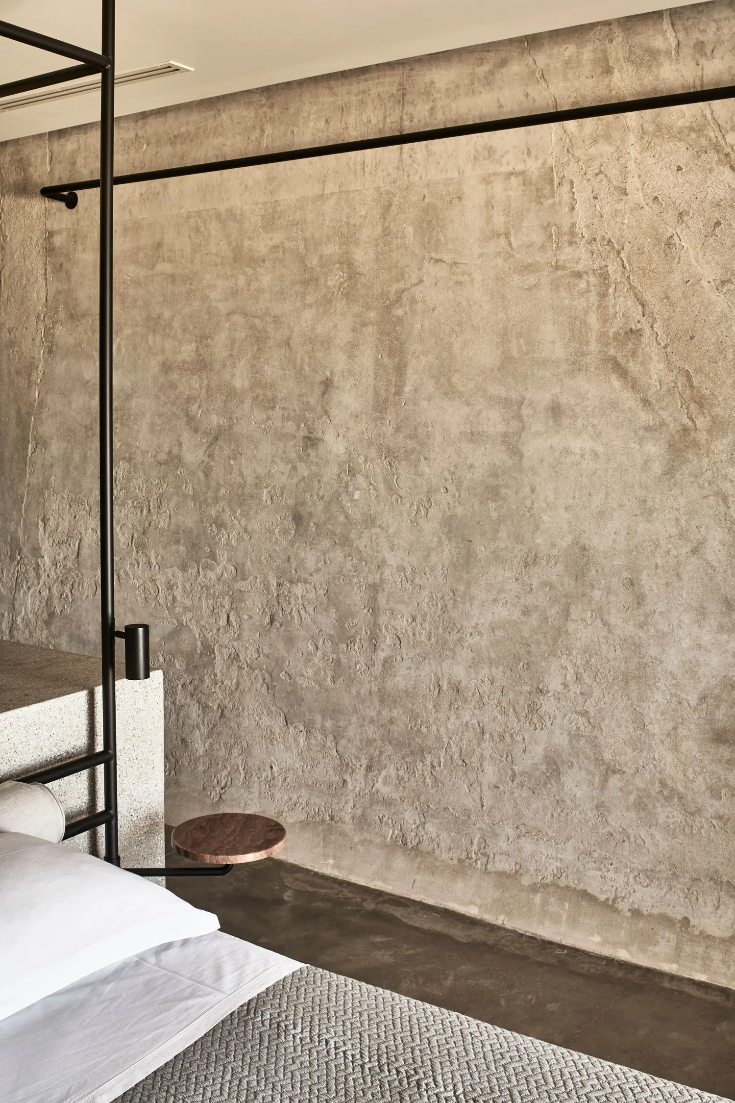 Minimalist modern bedroom featuring concrete walls and minimalist furniture.