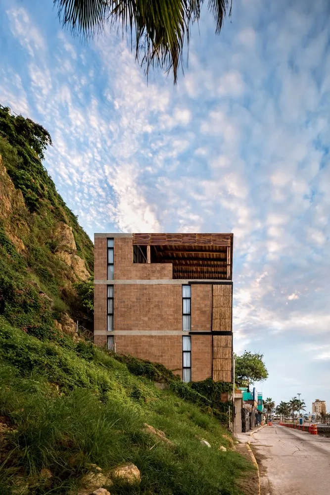 一座以混凝土建造的現代建築,坐落於綠草如茵的山坡上,背景是藍天。
