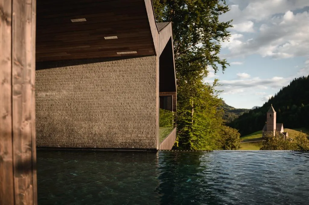 Modern wooden building with concrete facade in a Swiss Alps setting.