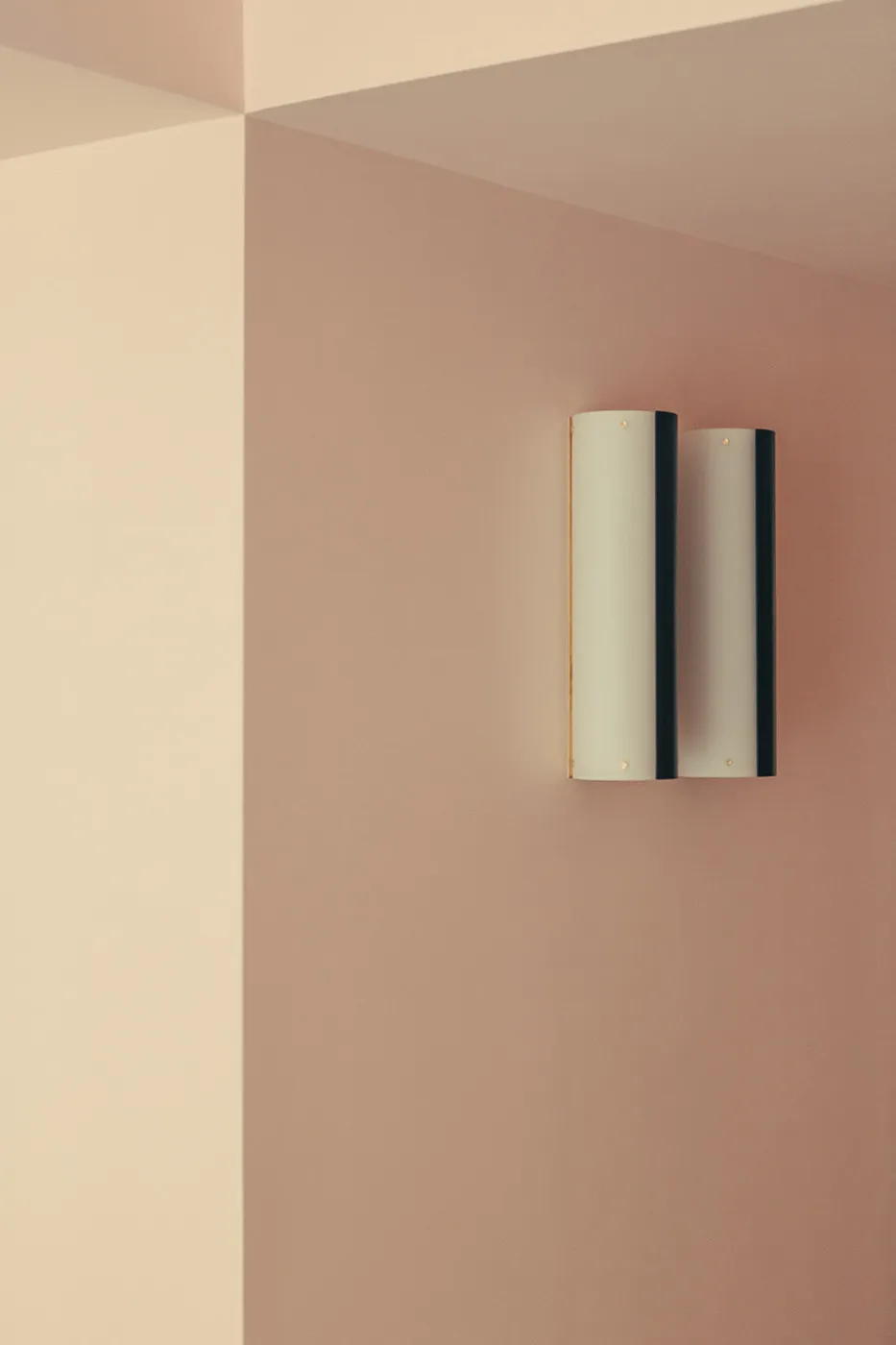 Modern metallic sconces mounted on a pink retail interior wall, highlighting clean lines and minimalist design.