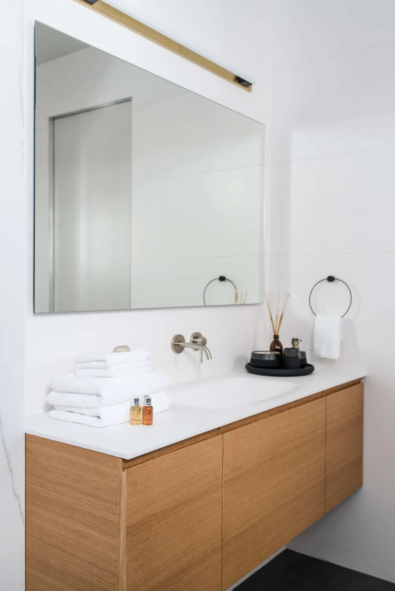 Modern bathroom with wooden vanity, marble countertop, and white towels