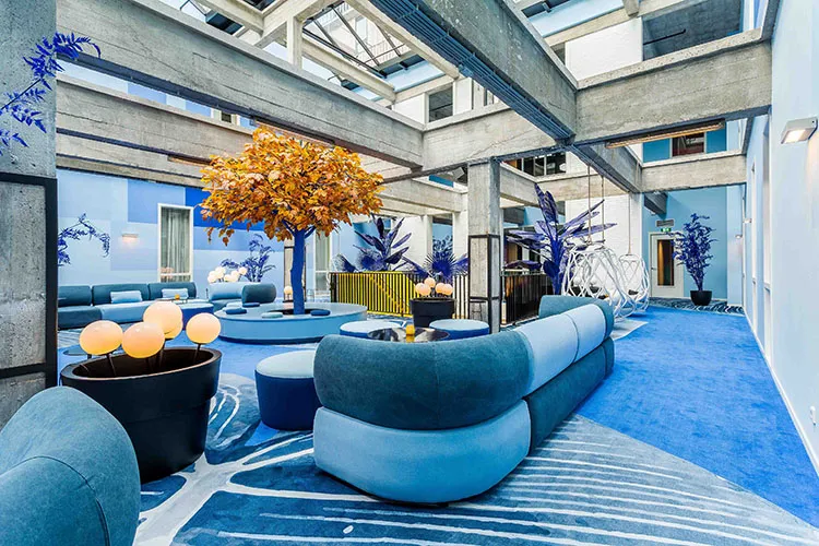 Lobby area with a modern blue sofa, concrete columns, and potted plants