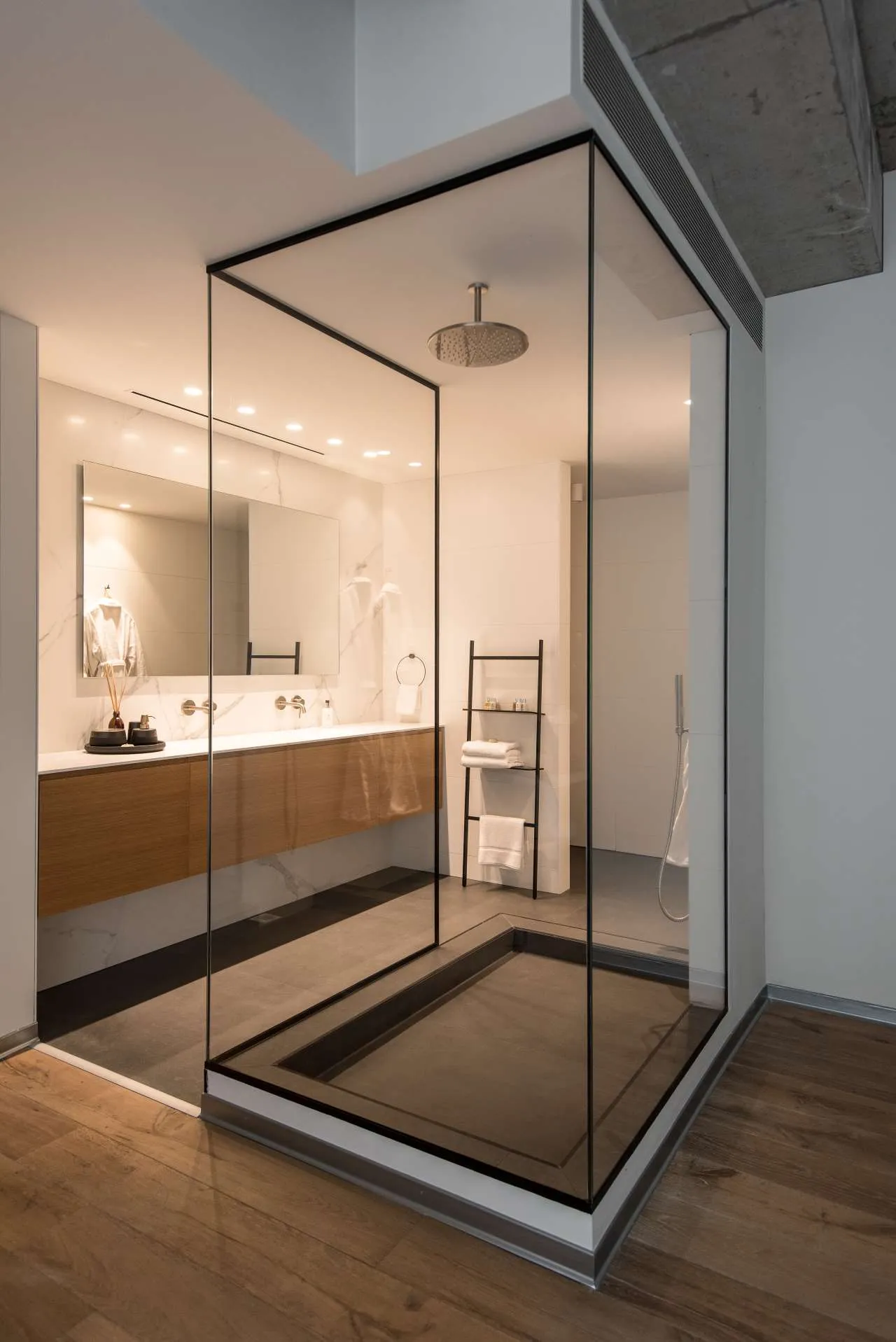 Modern minimalist bathroom with glass shower enclosure and marble accents.