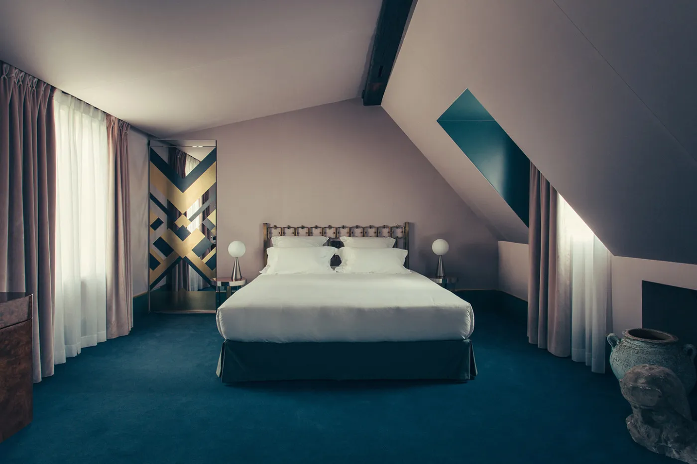 Modern minimalist bedroom with textured white walls and a bed adorned with a white bedspread and pillows. Room features simpl