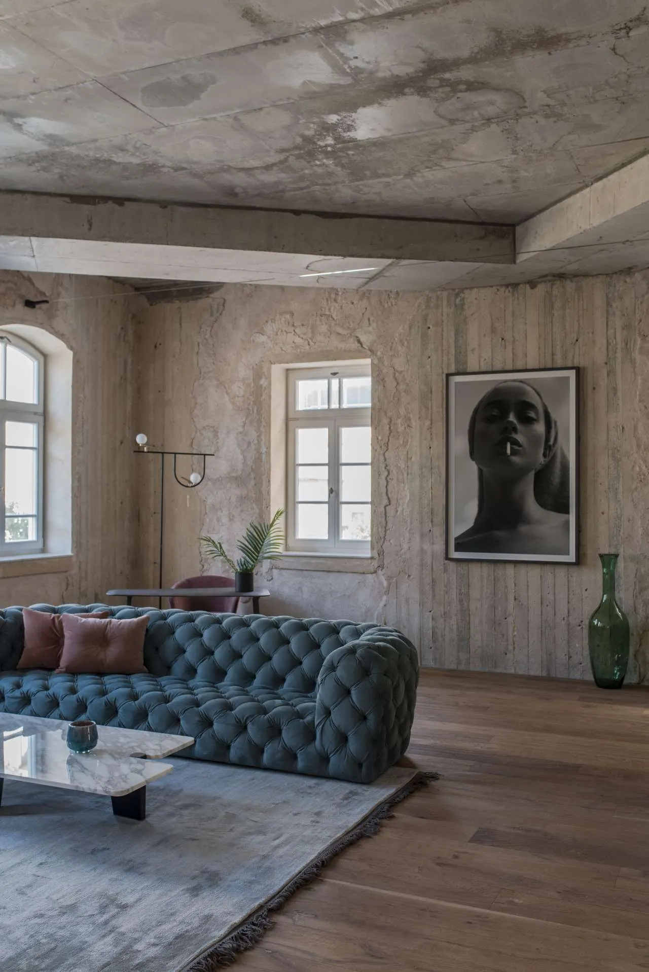 Modern living room interior with concrete walls, grey sofa, and minimalistic decor.