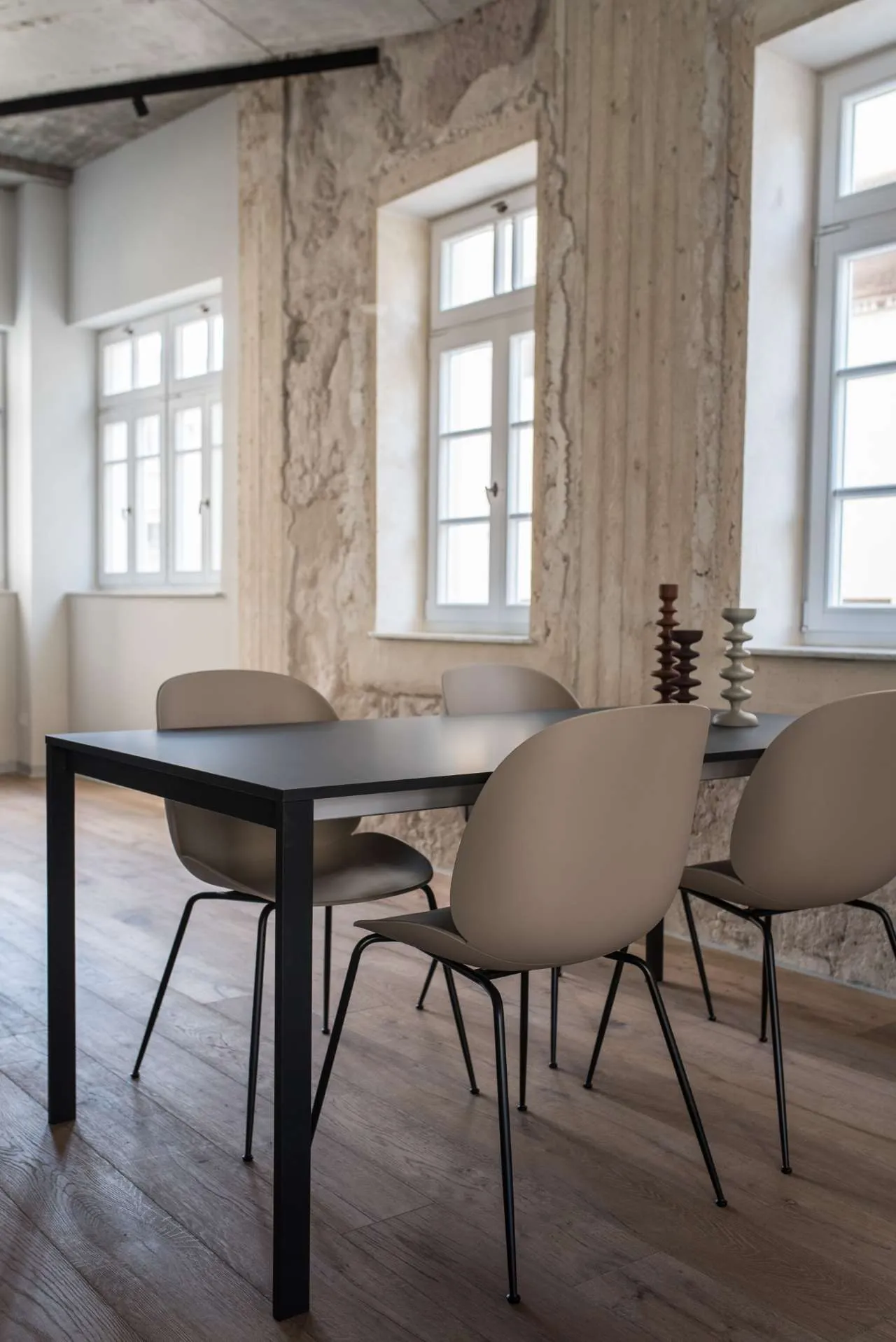 A modern dining room featuring a metallic table with four chairs and decorative candle holders on the table.