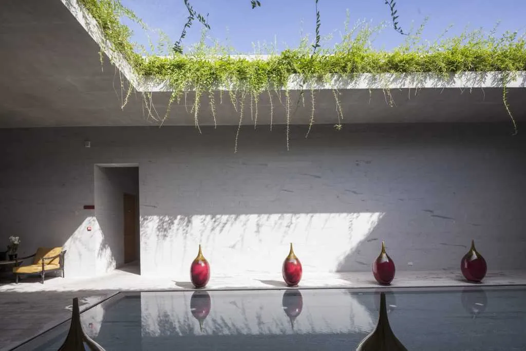 A modern pool with concrete walls and glass features.