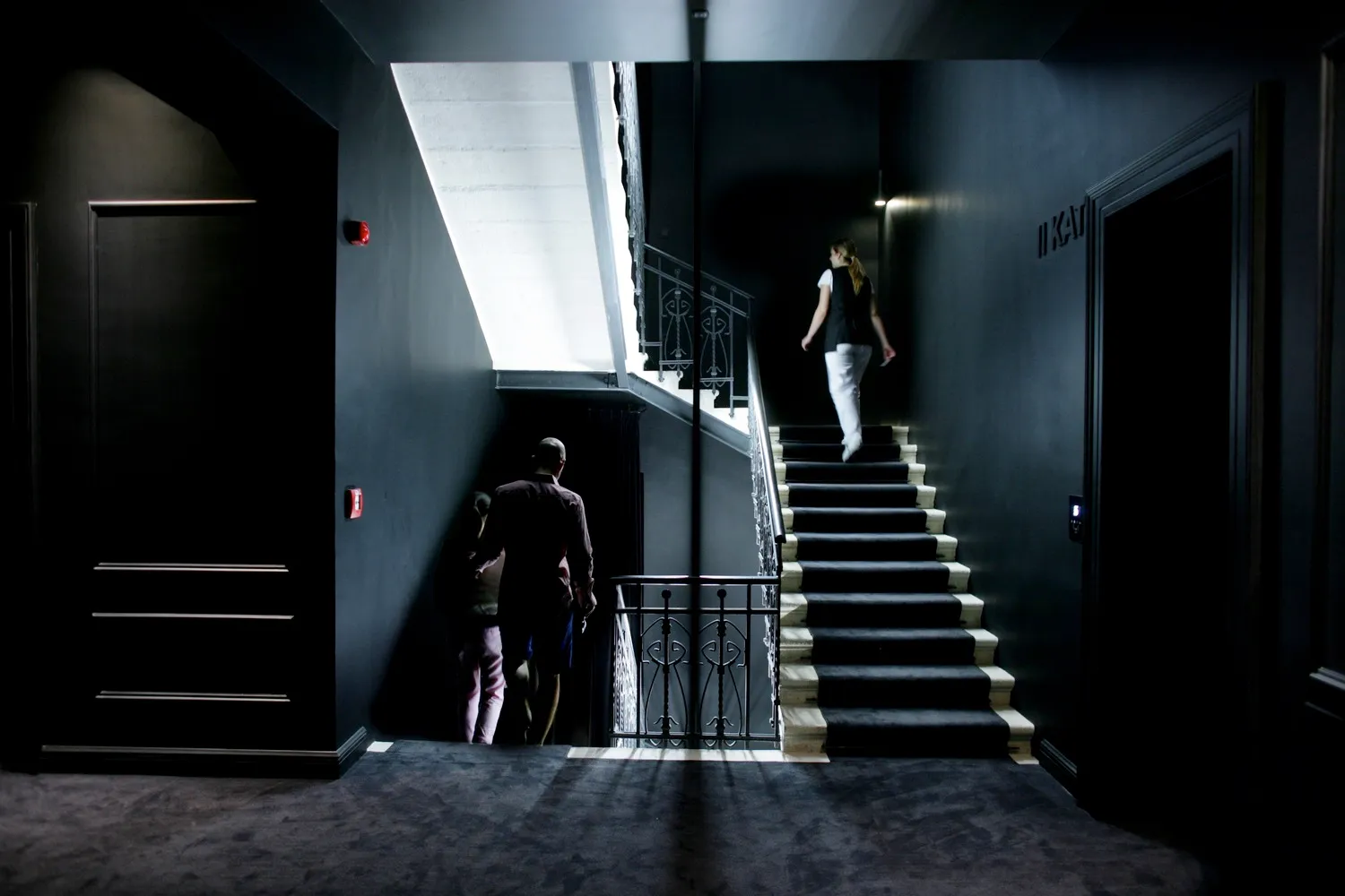 A modern hotel staircase with metal railings and black walls.