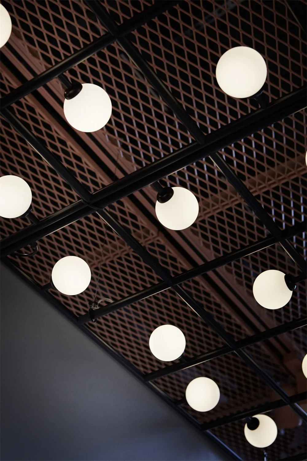 A modern, industrial-style ceiling grid with spherical light fixtures.