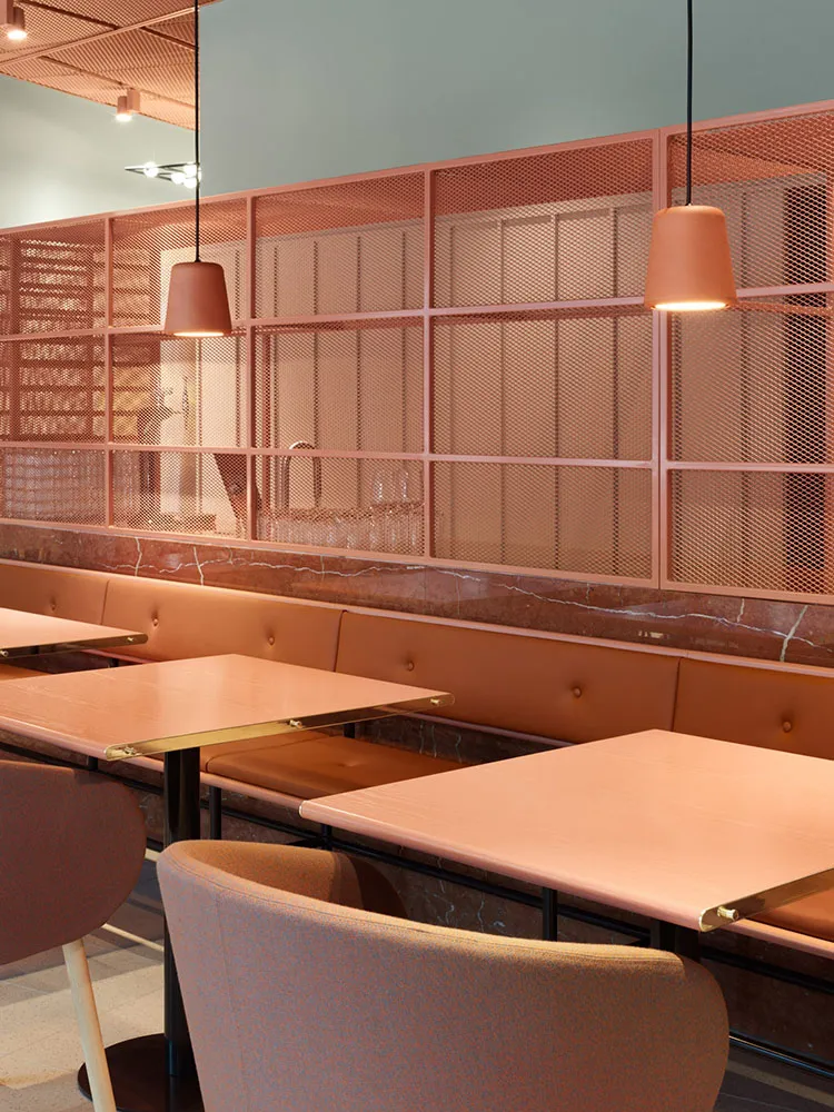 A modern restaurant interior with a unique design featuring a mesh partition made of metal rods and a marble counter top.