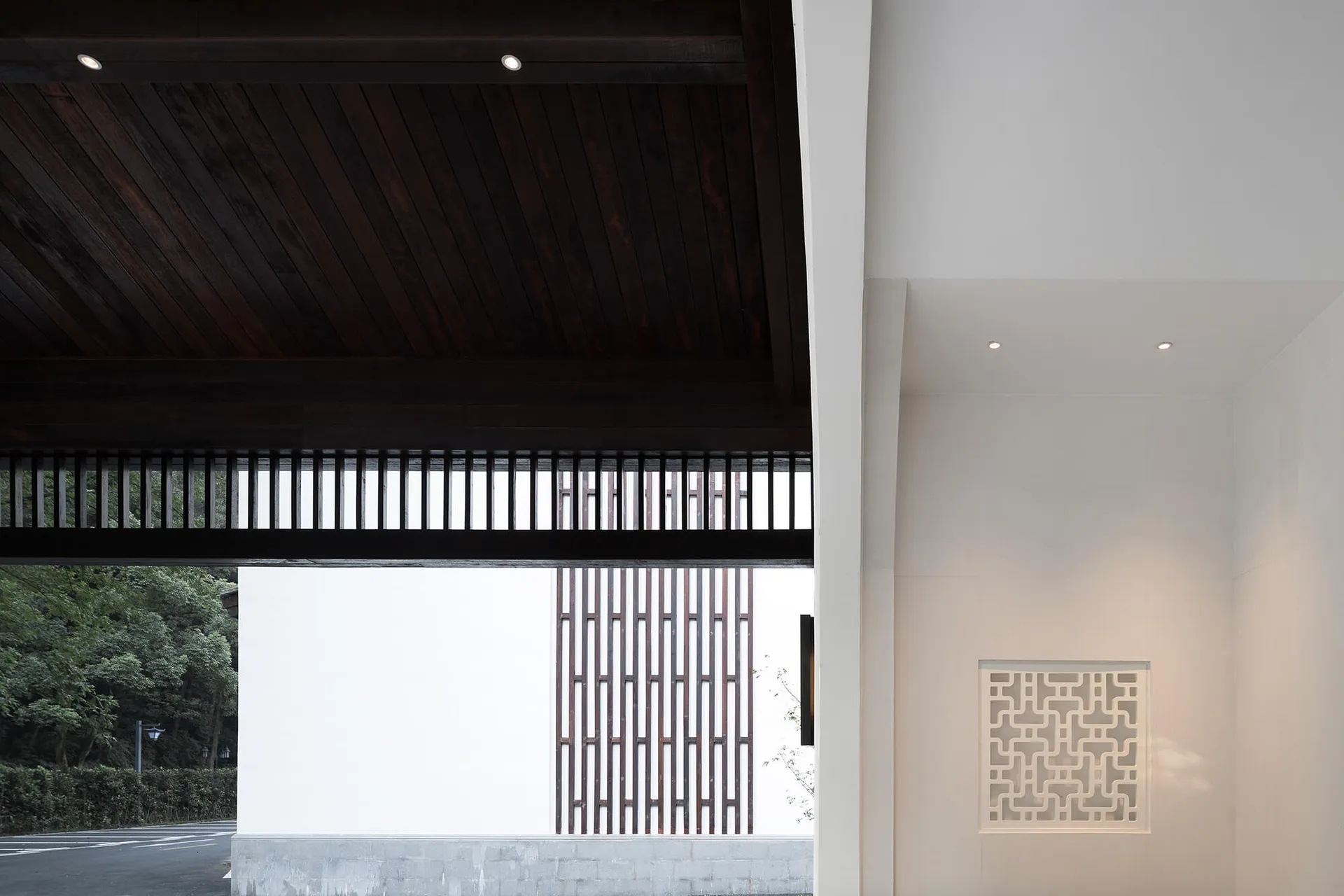 A minimalist entryway featuring wooden cabinets with geometric patterns, concrete walls, and paper lanterns.