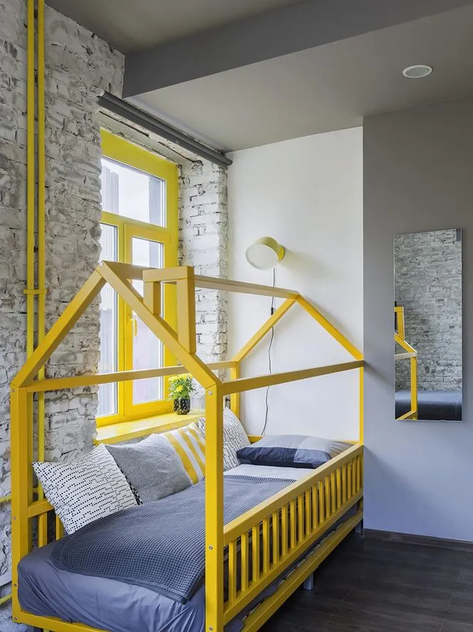 Minimalist bedroom featuring a yellow wooden frame bed with grey bedding and decorative pillows.