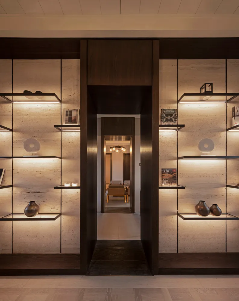 A modern entrance featuring a minimalist design with concrete floating shelves and dark wood accents.