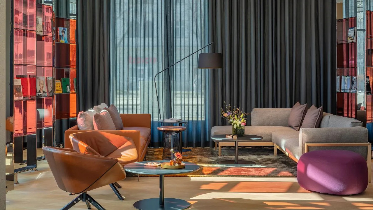 A contemporary living room with modern furniture, a mix of materials, and large windows.