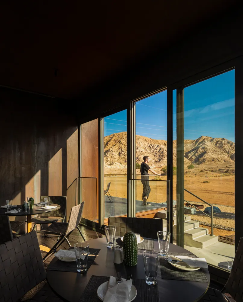 A modern restaurant interior with concrete, glass, and stainless steel elements.